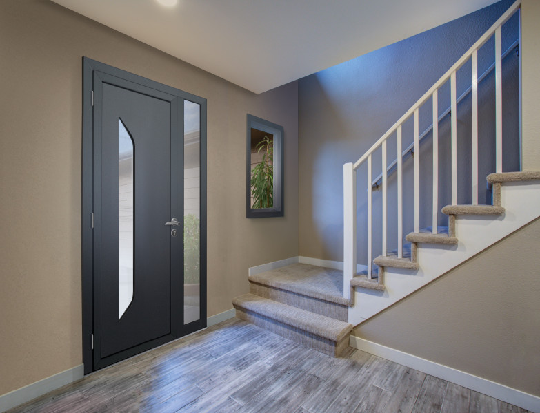 Porte d'entrée PVC Indus - Visuel d'ambiance Intérieur de maison moderne aux couleurs foncées et chaleureuses avec porte d'entrée grise